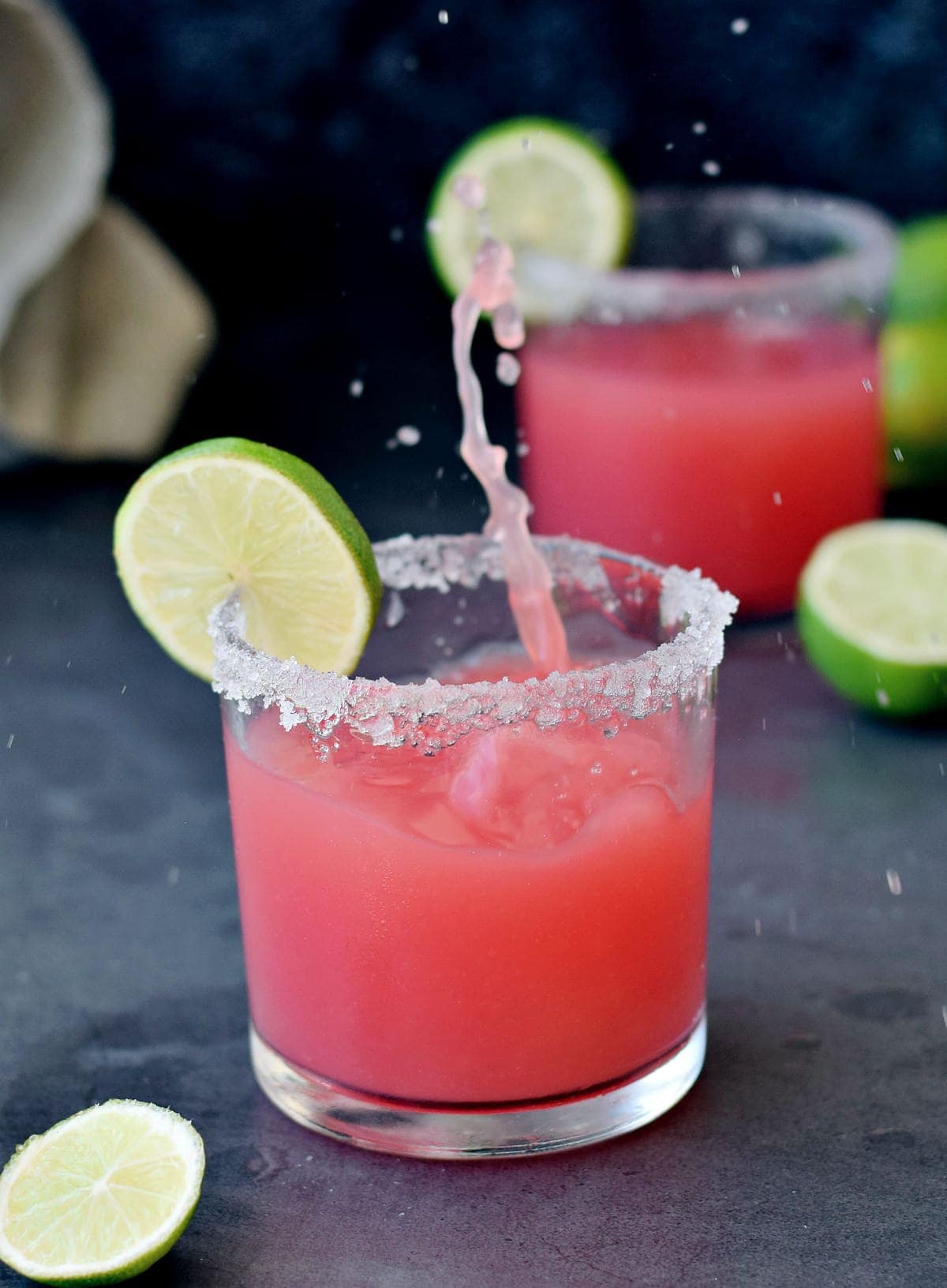 splash shot of margarita in glass with watermelon and lime