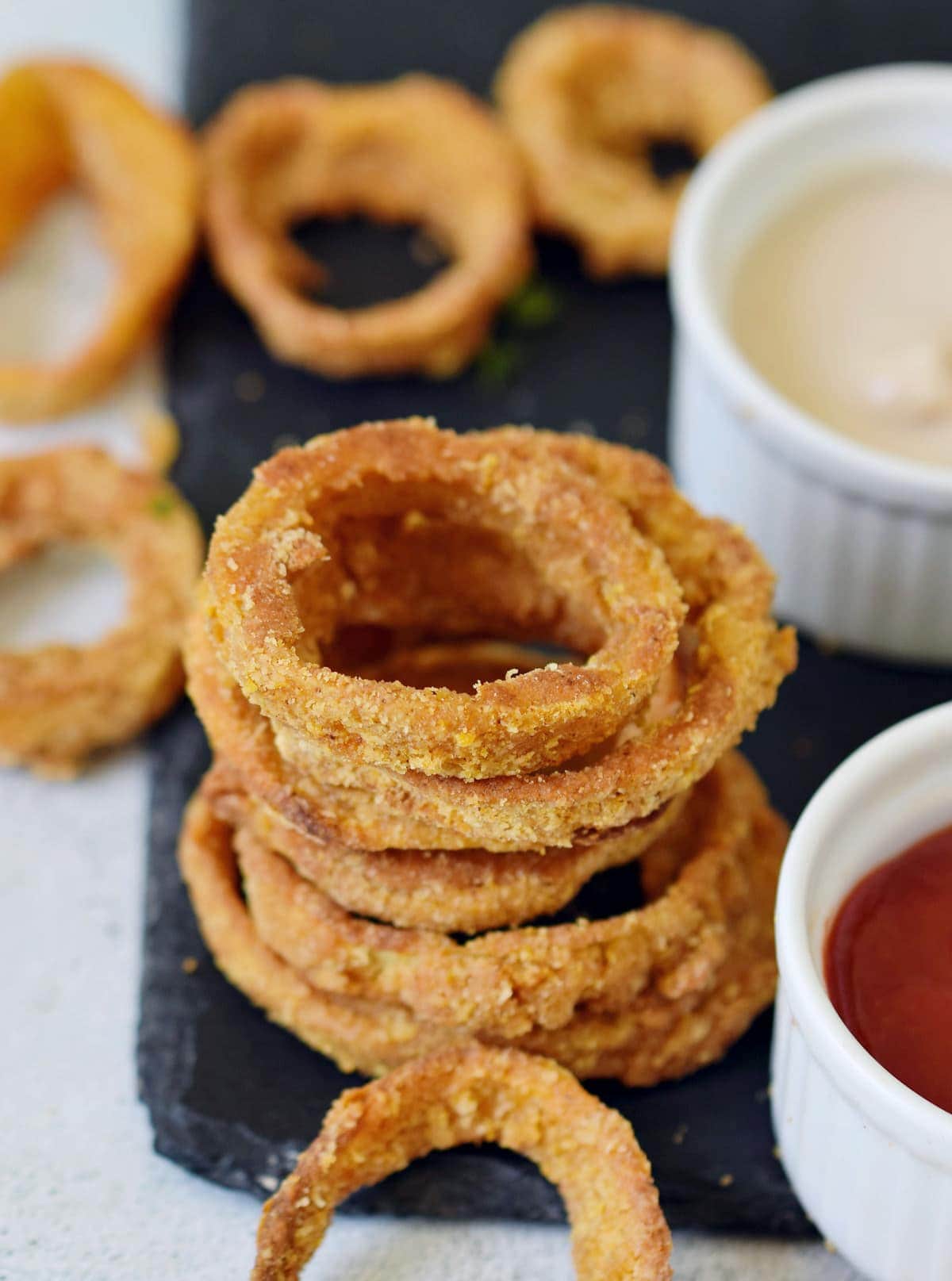 stack of vegan onion rings with dips