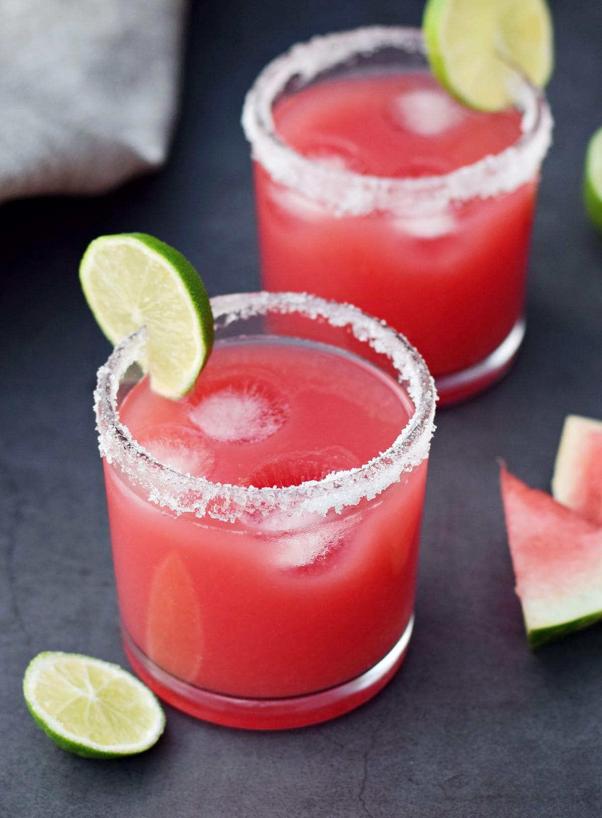 watermelon tequila drink with lime slices and salt rim