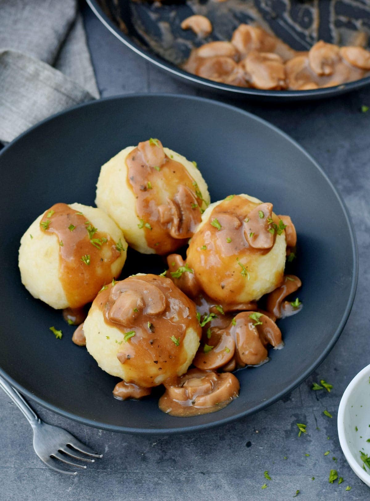 4 potato dumplings with mushroom sauce in a black bowl