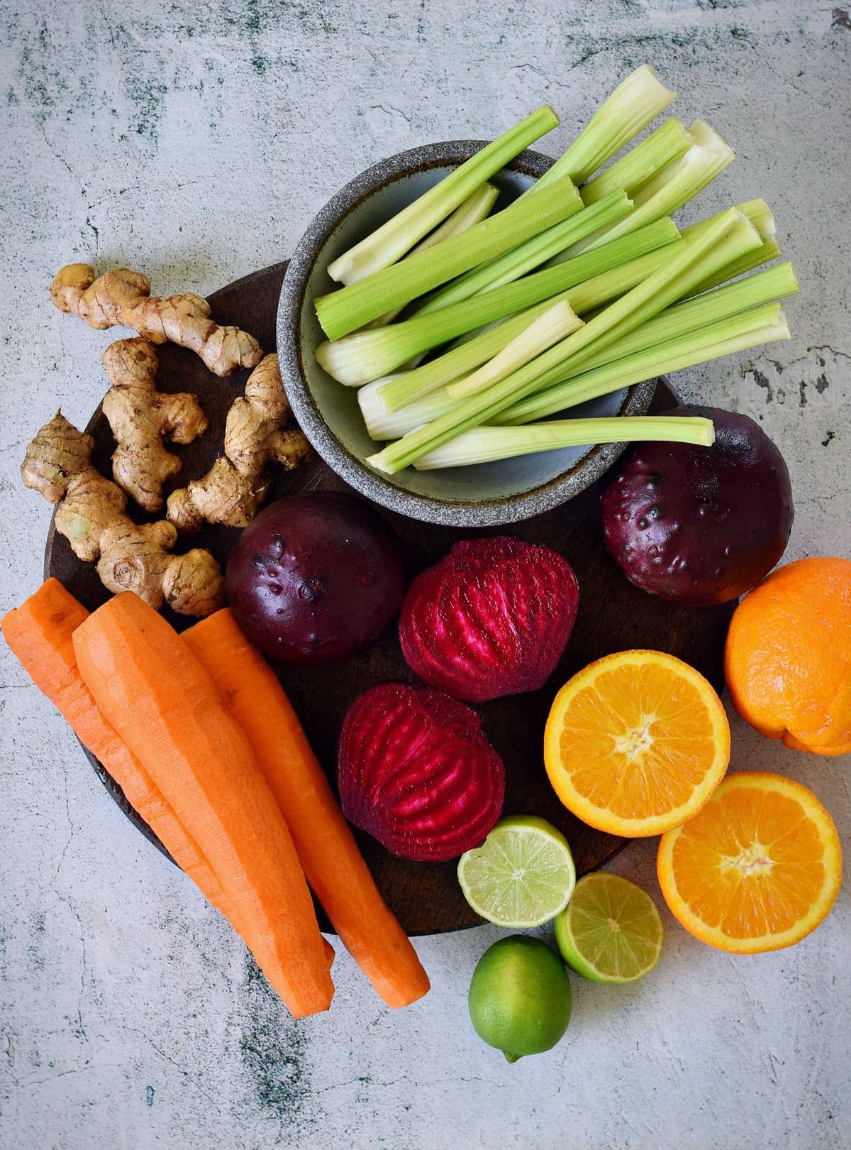 carrots, celery, beetroot, limes, ginger, oranges on cutting board
