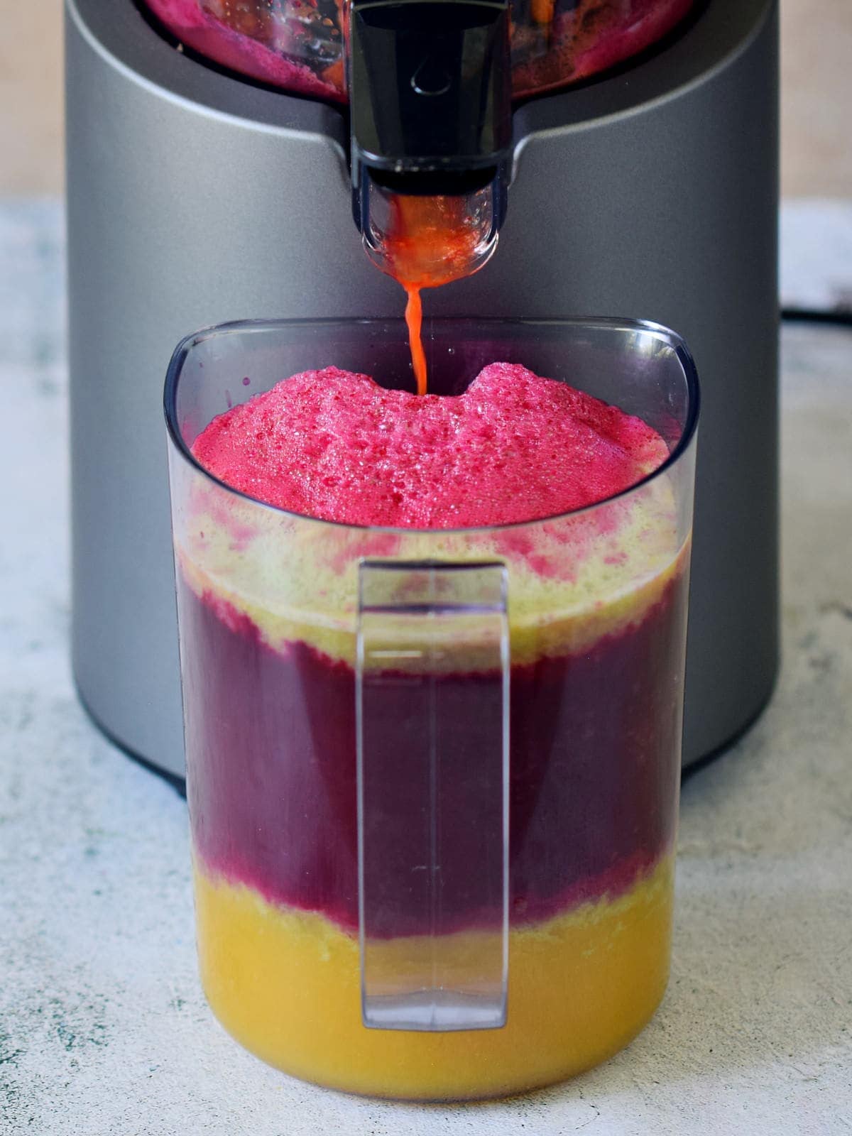 colorful juice in jug in front of juicer