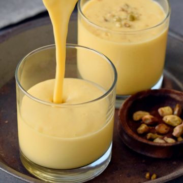 mango lassi is being poured in a glass