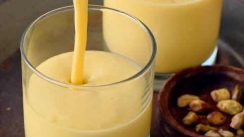 mango lassi is being poured in a glass