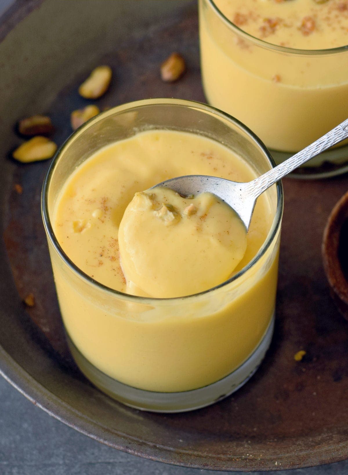spoon over glass of mango lassi