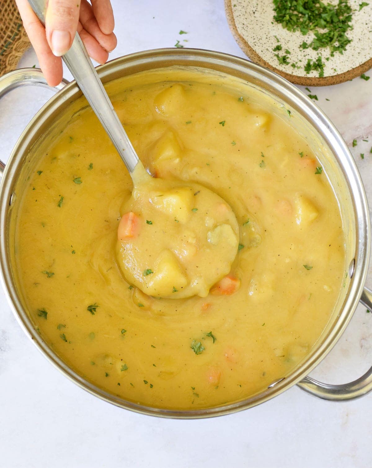 A large pot filled with German potato soup (vegan) and a ladle from above