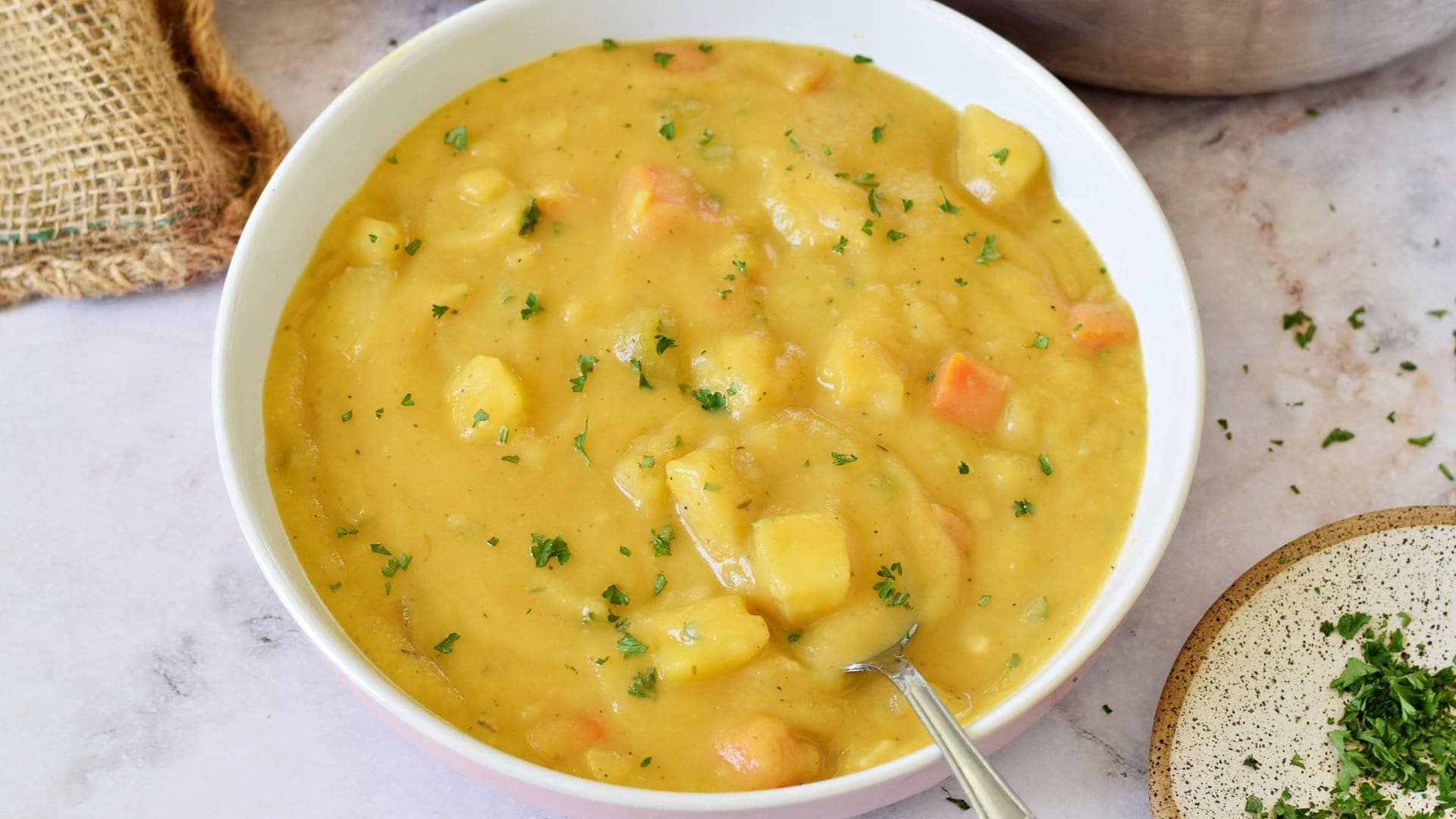 Kartoffel-Möhren-Suppe mit Löffel in Schale