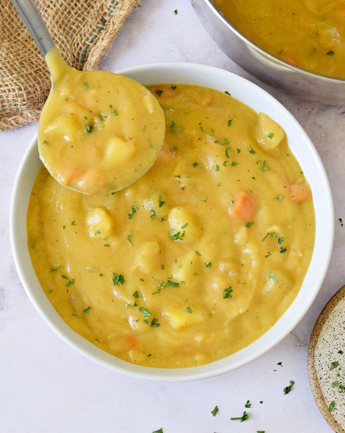 Ladlle over bowl with chunky vegan potato soup