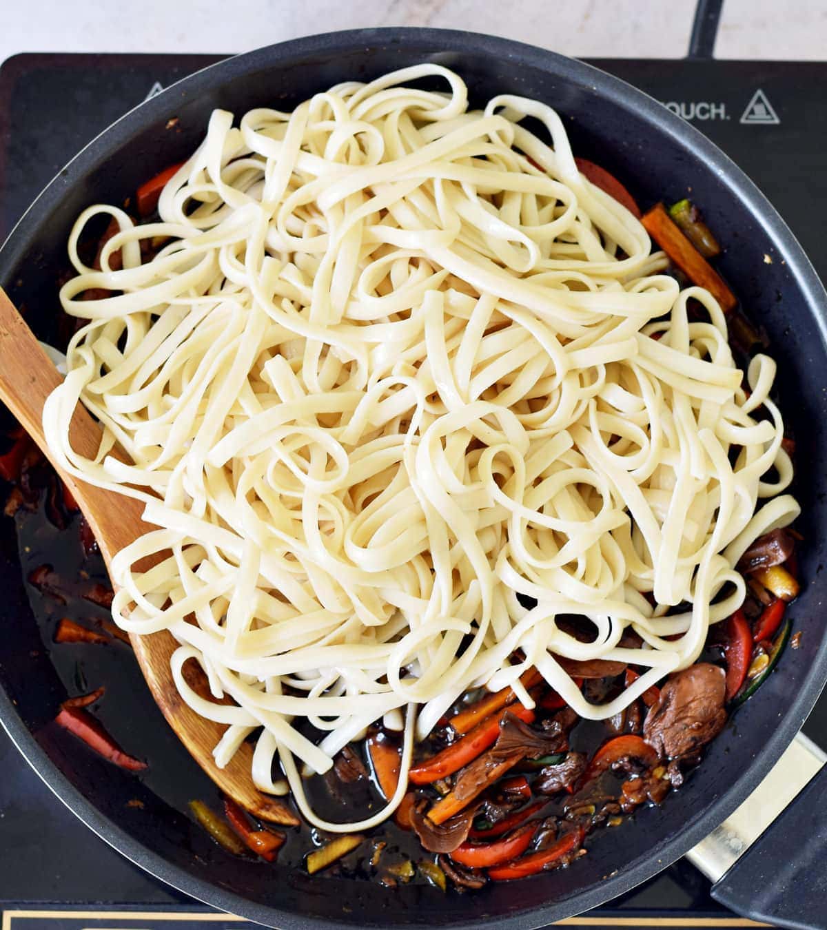 cooked pasta on veggies in pan Asian vegetarian noodle dish