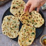 gluten-free naan bread on a plate with hand pinching one