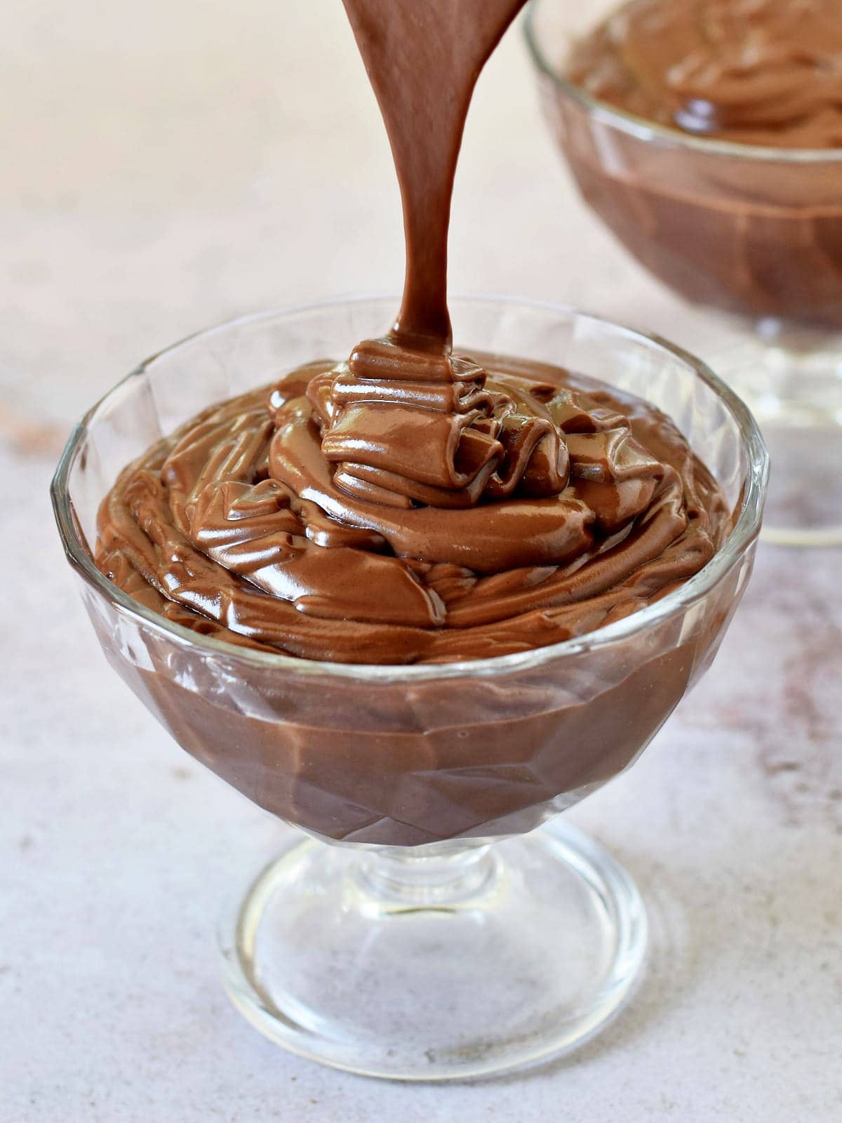 pouring cooked chocolate pudding in a wide jar