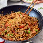spicy Sriracha noodles in black skillet with chopsticks