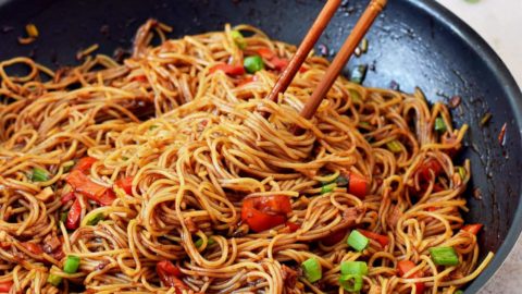 spicy Sriracha noodles in black skillet with chopsticks