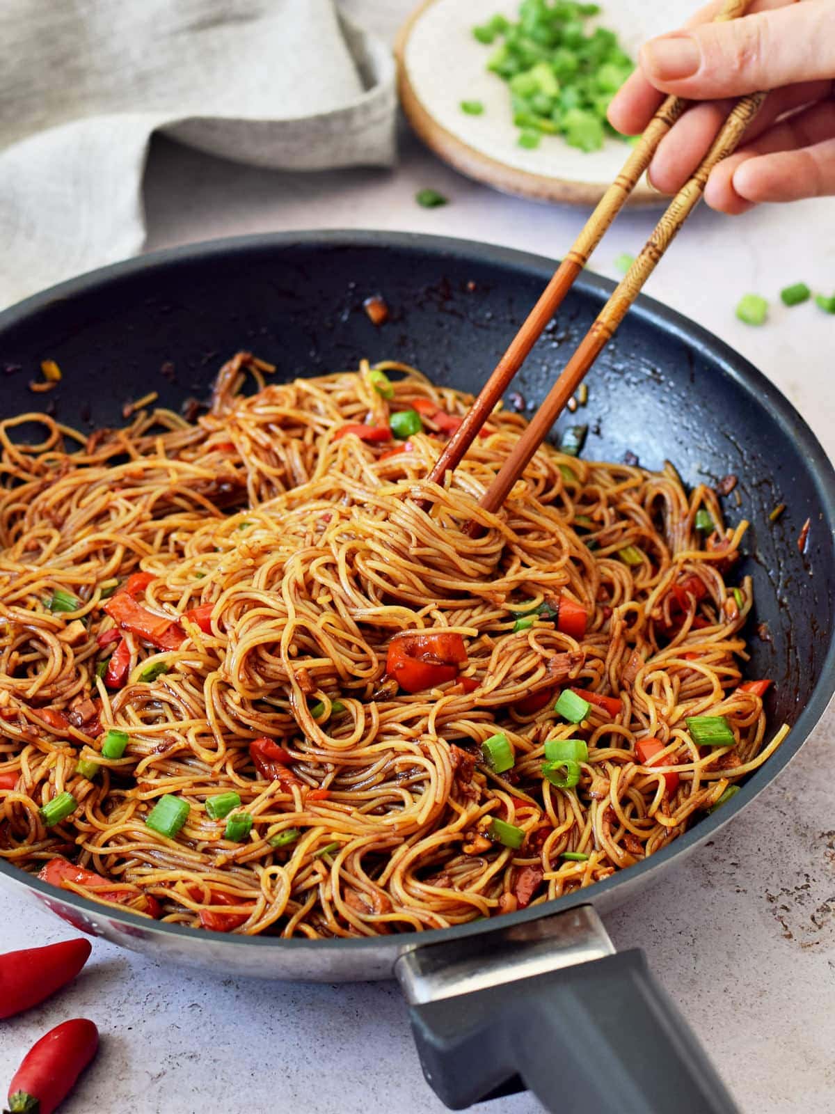 spicy Sriracha noodles in black skillet with chopsticks