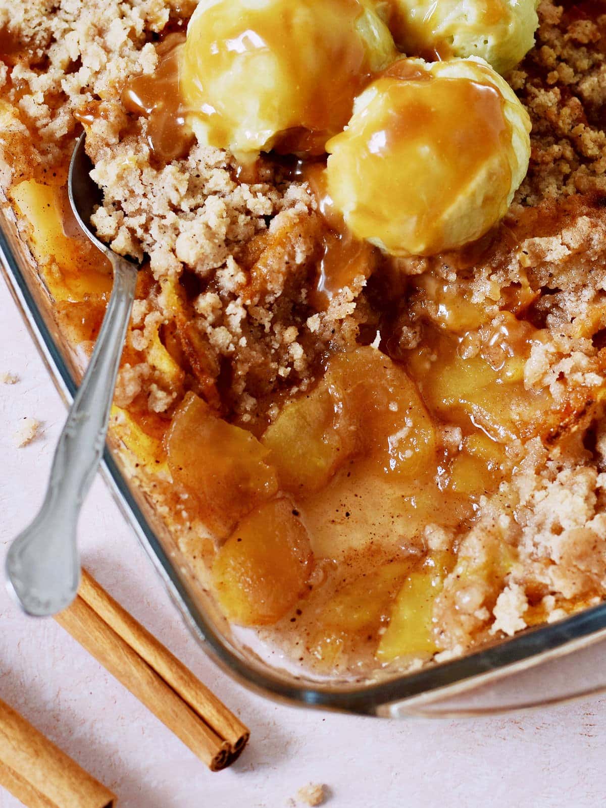 close-up of apple crisp with ice cream in baking dish with spoon