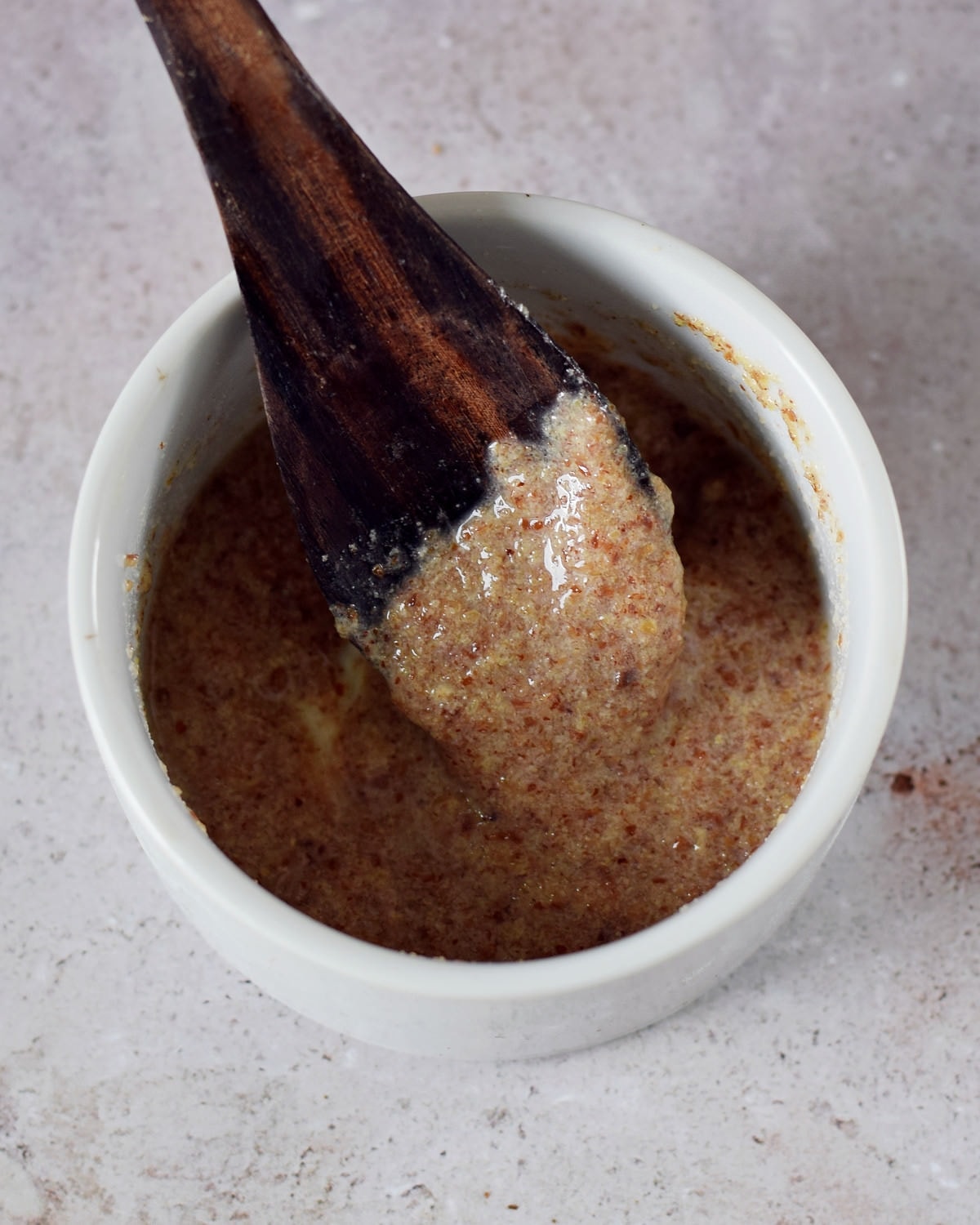 flax egg in small bowl with wooden spoon