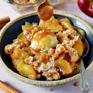 spoon drizzling vegan caramel over apple crisp (without oats) with ice cream on plate