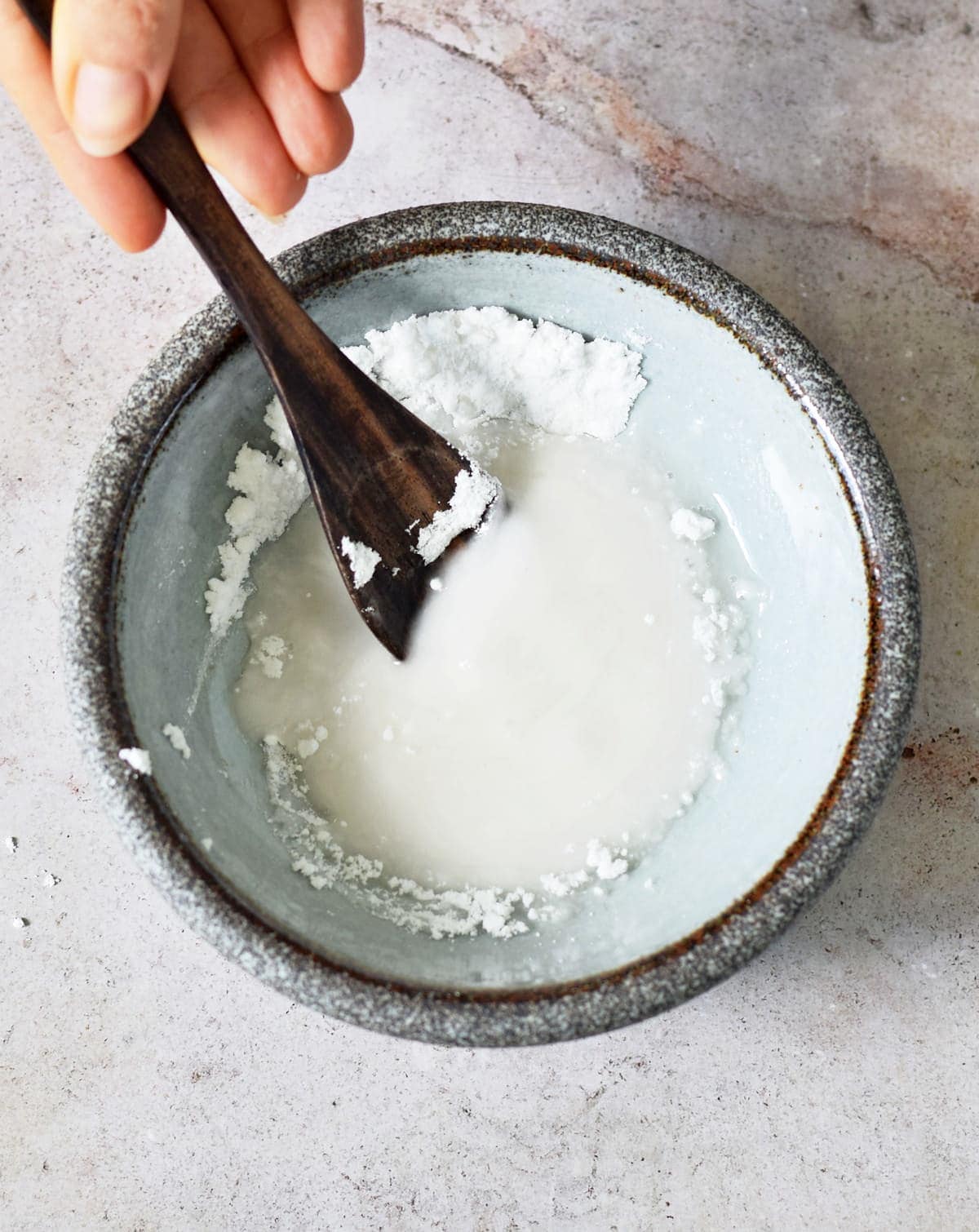 stirring icing sugar and water in bowl with spoon