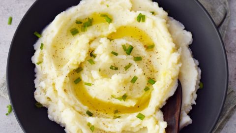 Eating vegan mashed potatoes in black bowl with olive oil drizzle