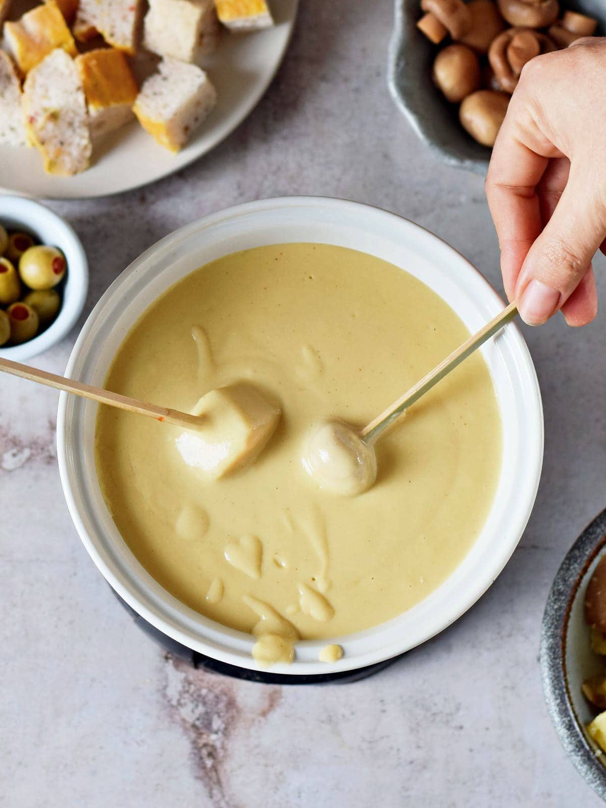 dipping bread in dairy-free cheese sauce