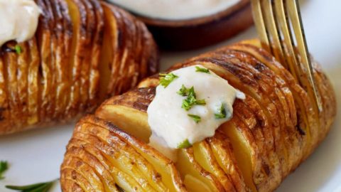 fork submerged in hasselback potato with dip