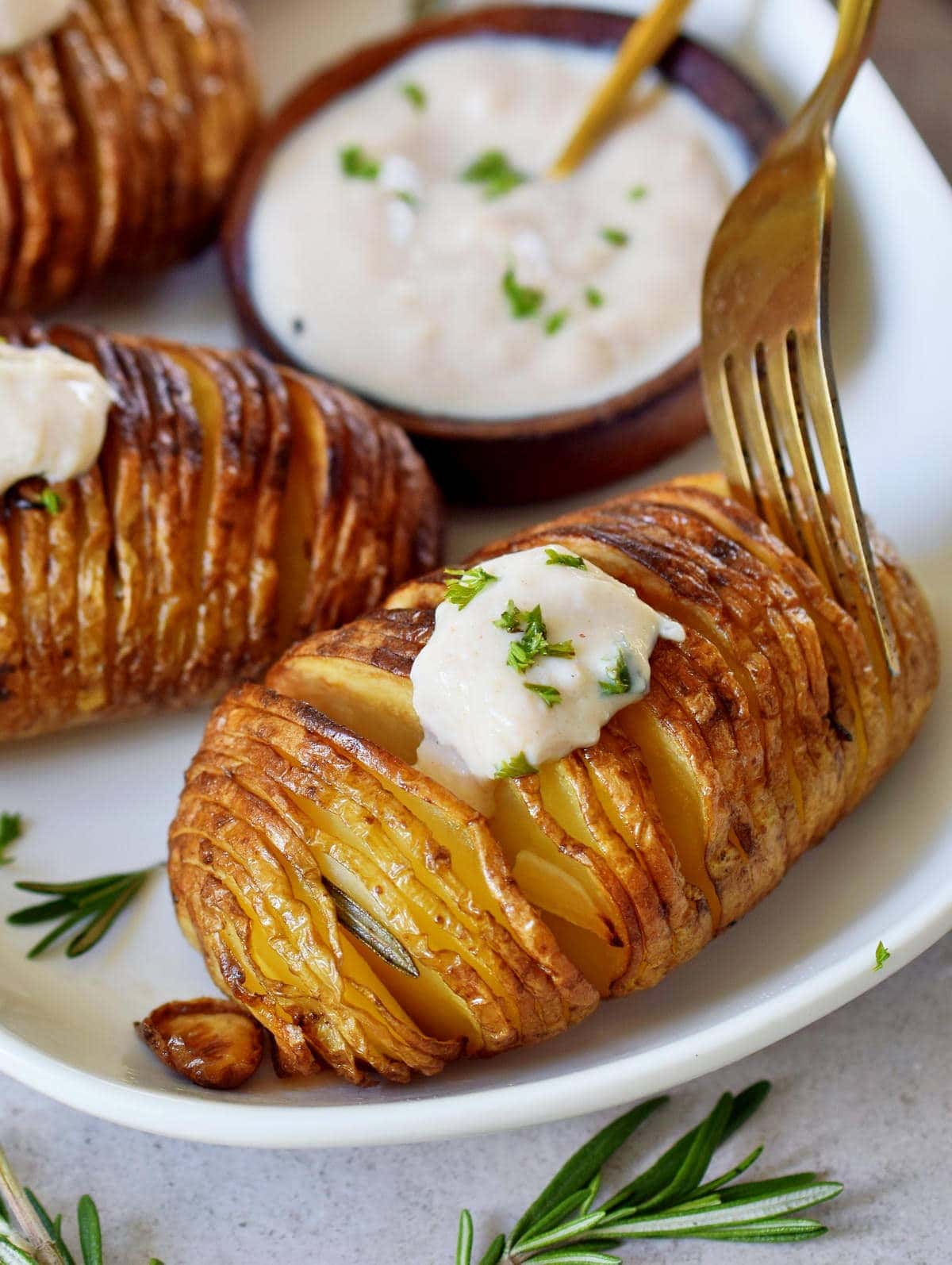 fork submerged in hasselback potato with dip