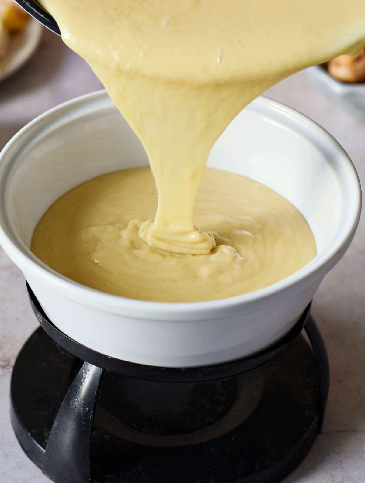 pouring vegan cheese sauce in white pot