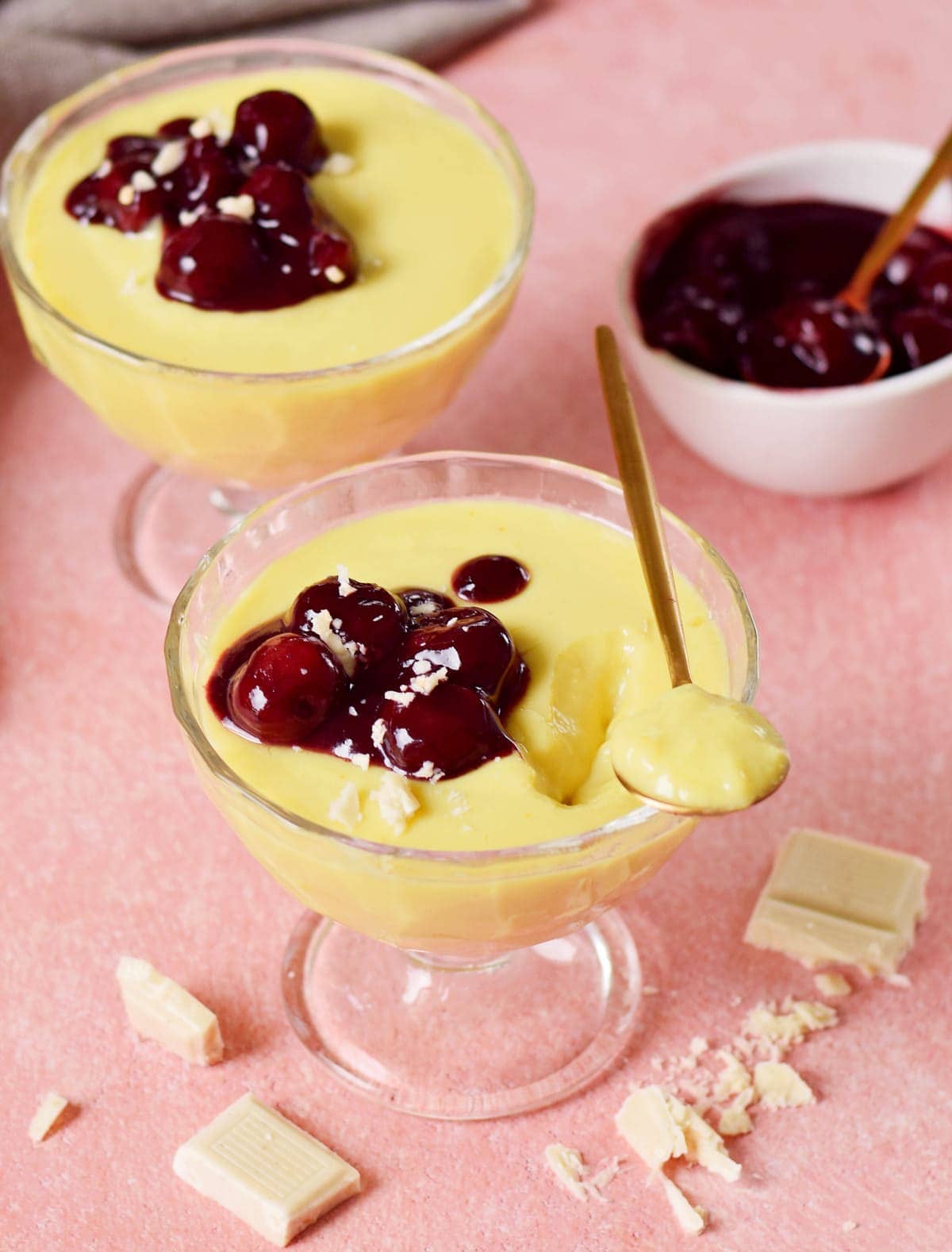 2 glasses vegan vanilla pudding with cherry compote and spoon