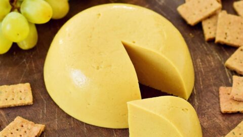 Best vegan cheese on wooden board with a piece cut out