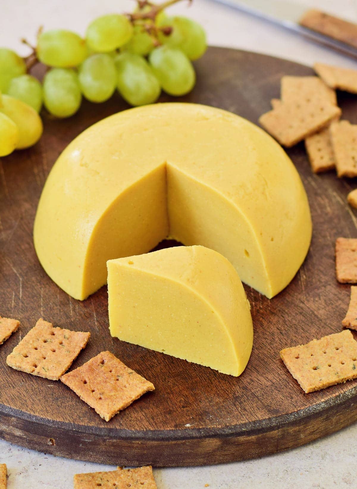 best vegan cheese with crackers and grapes on wooden board