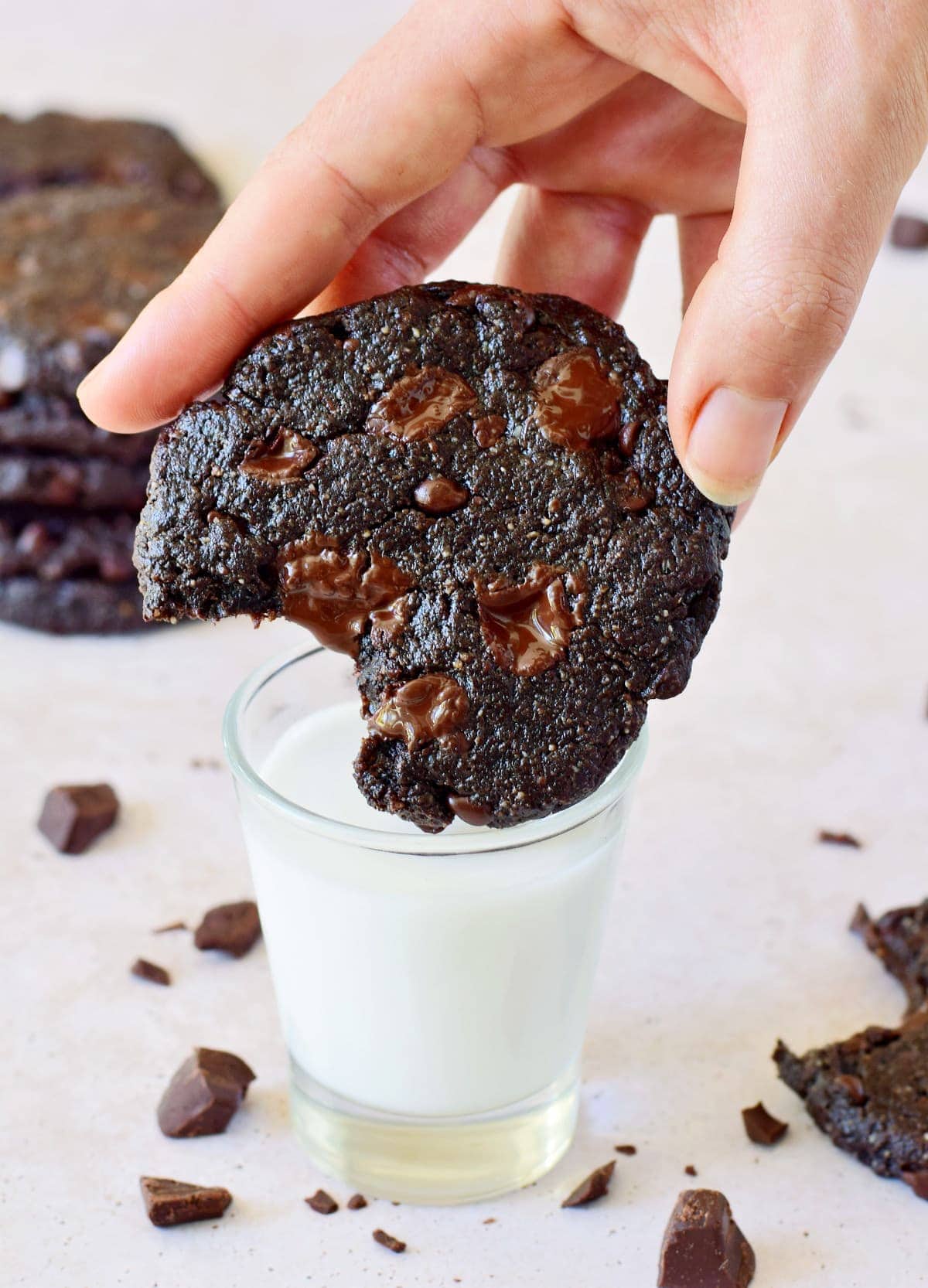 vegan double chocolate chip cookie dipped in a glass of milk
