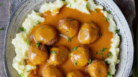 vegan meatballs with gravy over mashed potatoes in large bowl