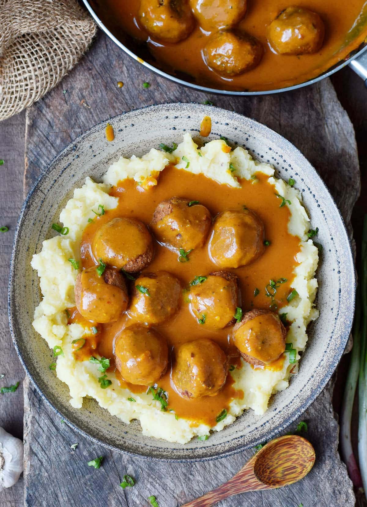 vegan meatballs with gravy over mashed potatoes in large bowl