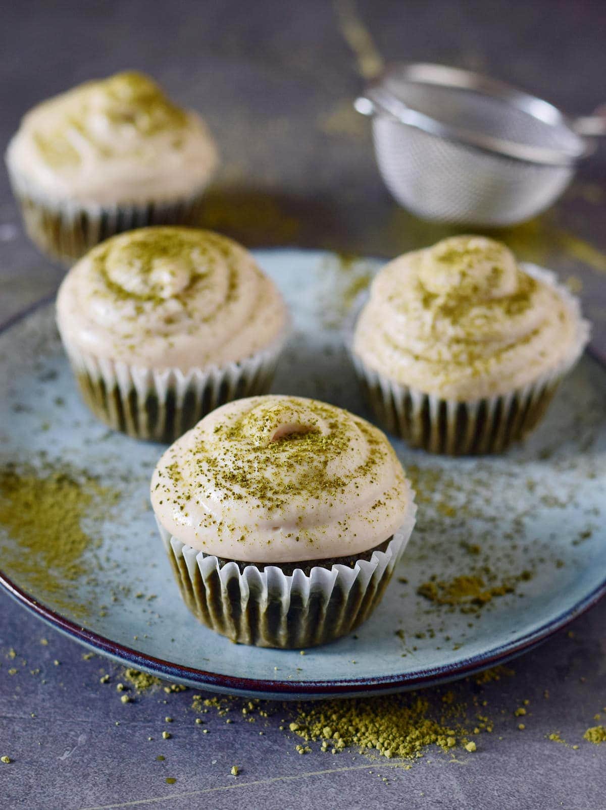 3 matcha cupcakes with white frosting sprinkled with green powder