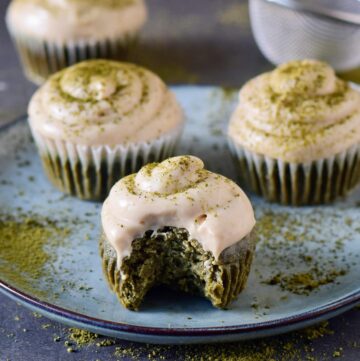 eating matcha cupcake with white frosting sprinkled with green powder
