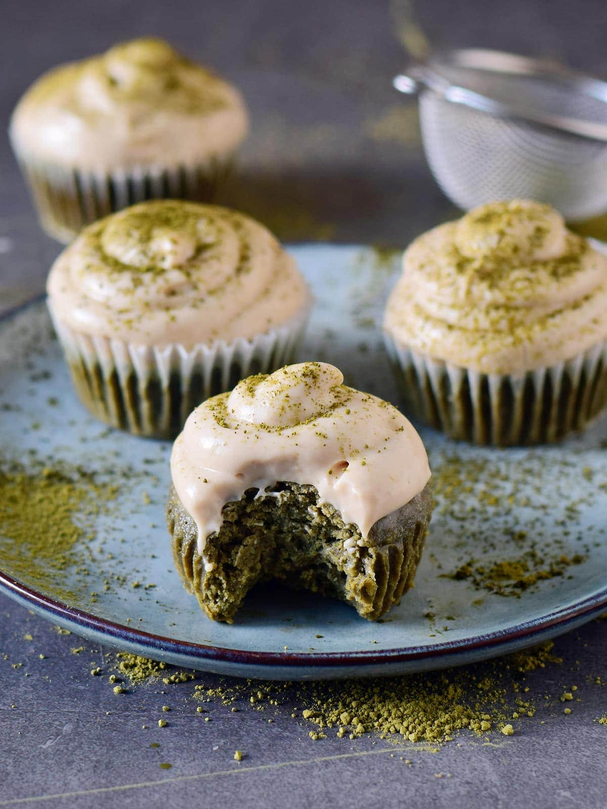 eating matcha cupcake with white frosting sprinkled with green powder