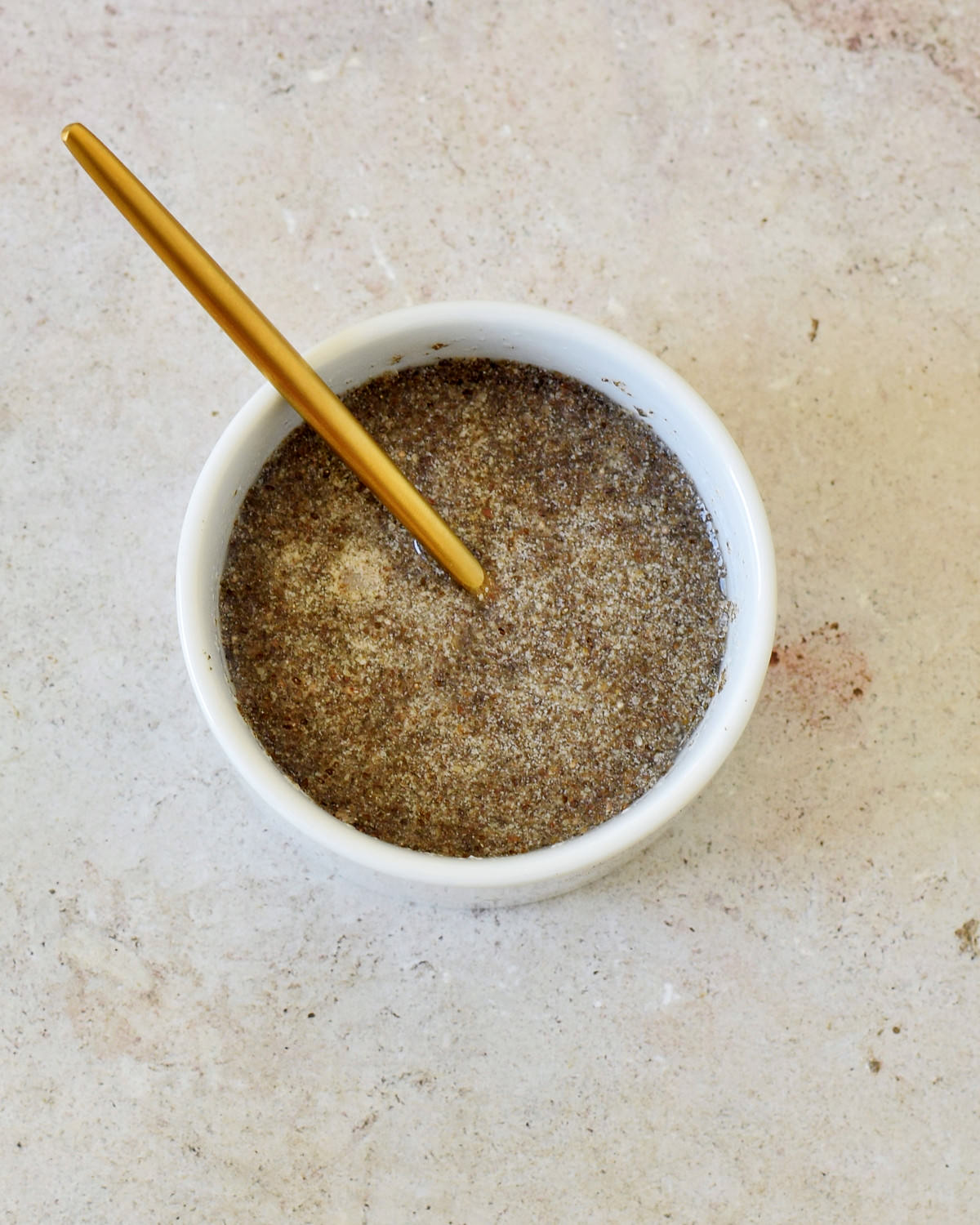 chia eggs in small white bowl with golden spoon