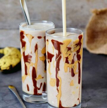pouring vegan milk shake in a glass drizzled with chocolate and peanut butter