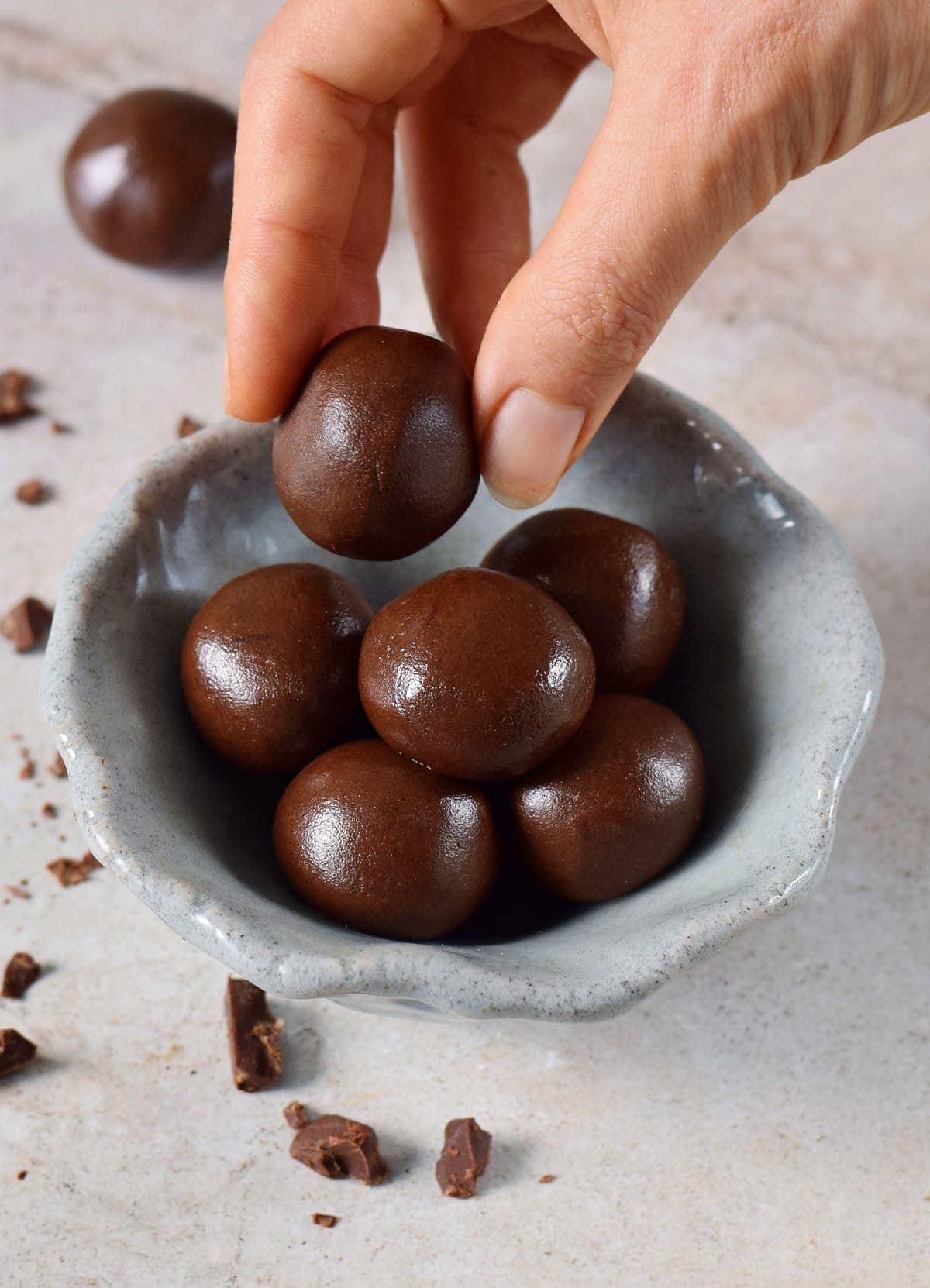 hand grabbing a chocolate fat bomb truffle from a bowl