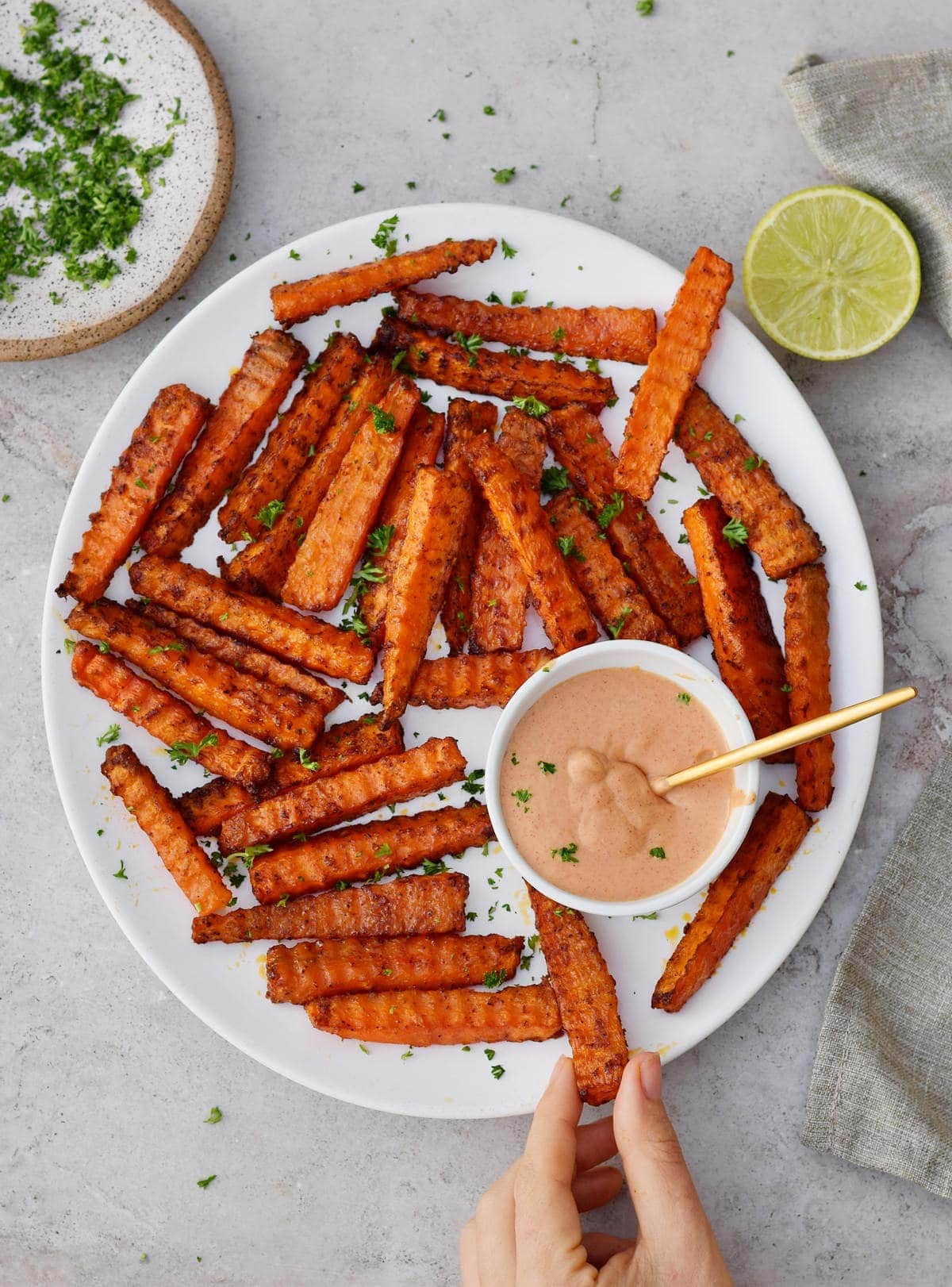 hand grabbing carrot fries from a white plate