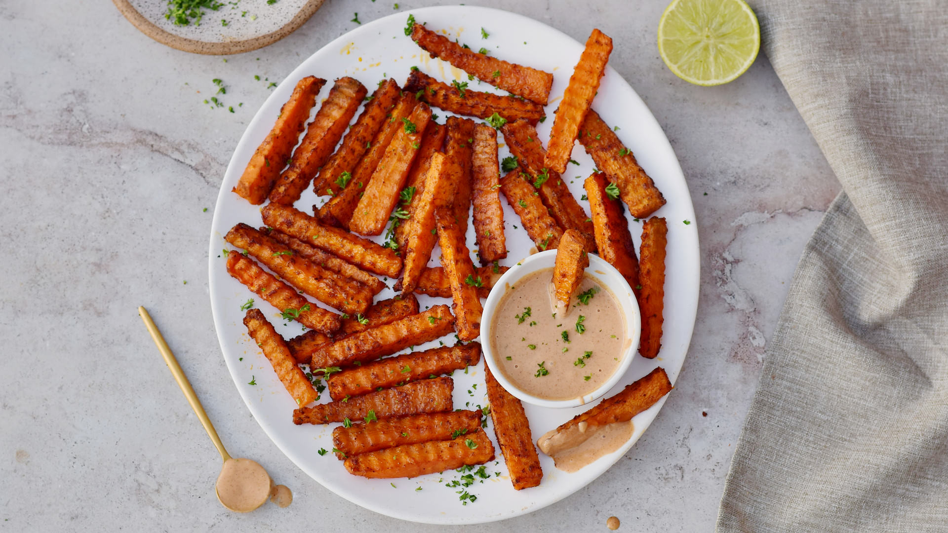 horizontal shot of carrot fries on white plate with pink dip