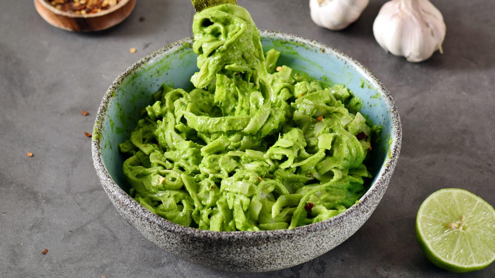 horizontal shot of creamy green pasta in bowl