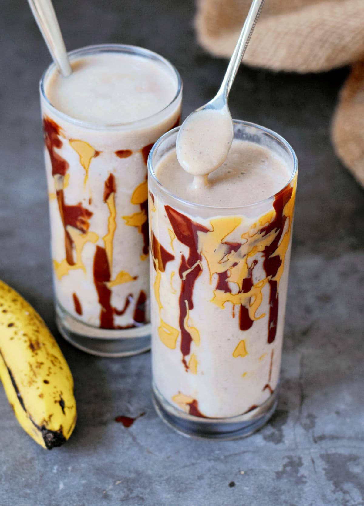 spoon over a glass filled with a creamy vegan shake drizzled with PB and chocolate
