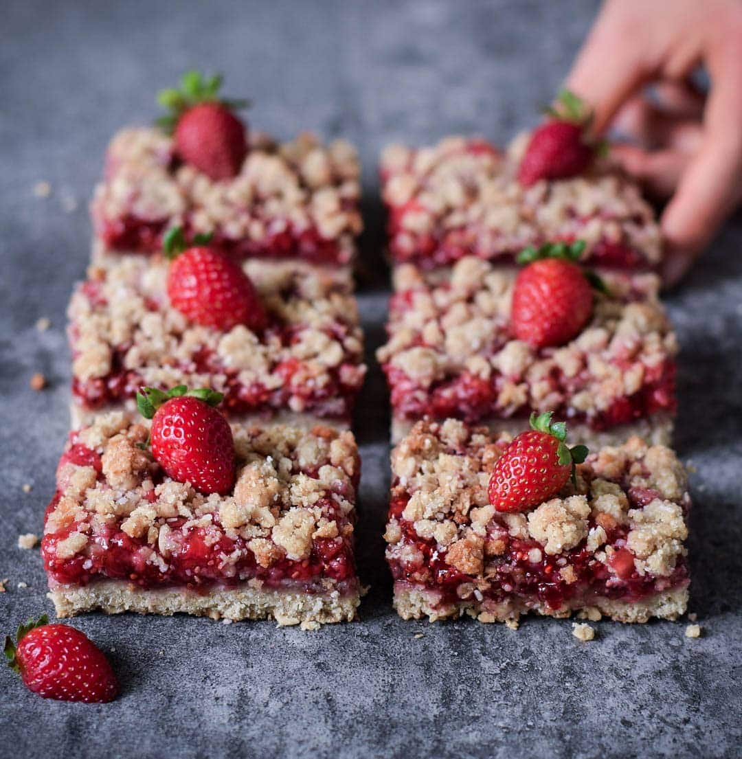 6 strawberry oatmeal bars in 2 rows with hand grabbing one
