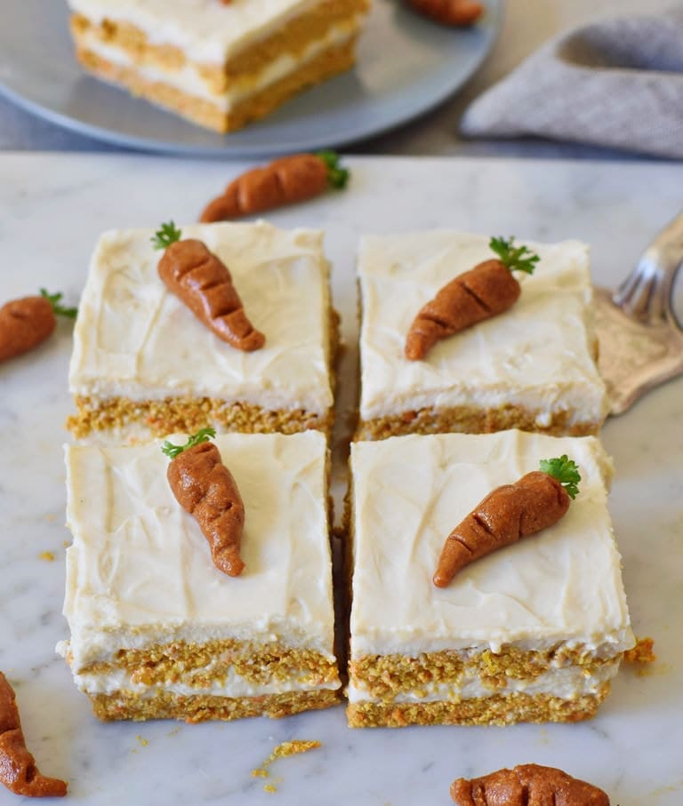 vegan carrot cake with a white cream and marzipan carrots on top