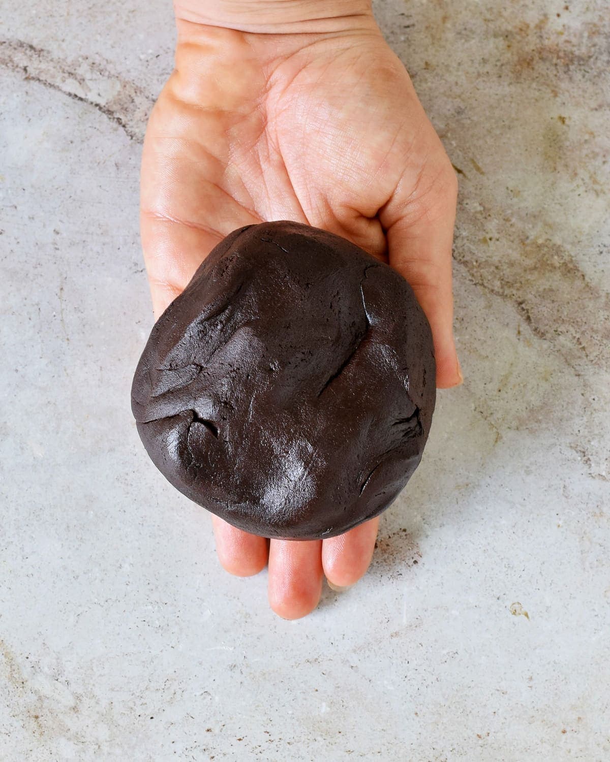Hand hält einen Schokoladenteig aus Kondensmilch und Kakaopulver