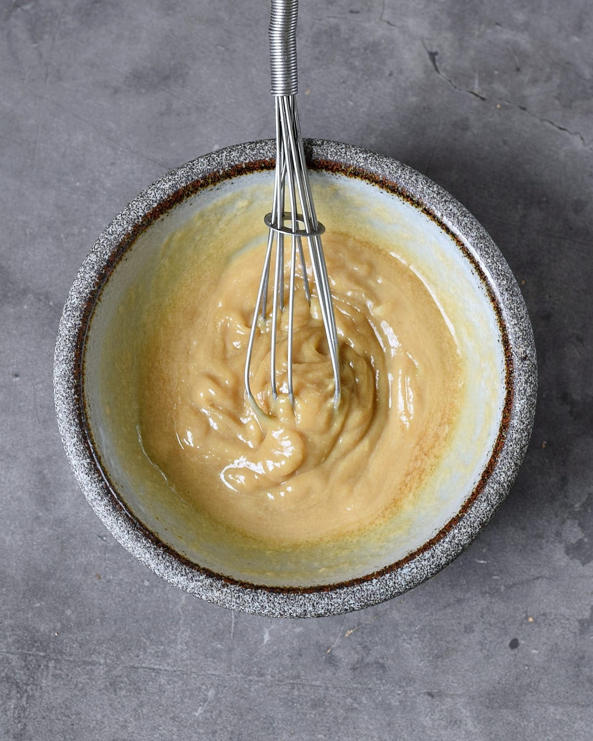 sesame paste with lemon juice in bowl with whisk