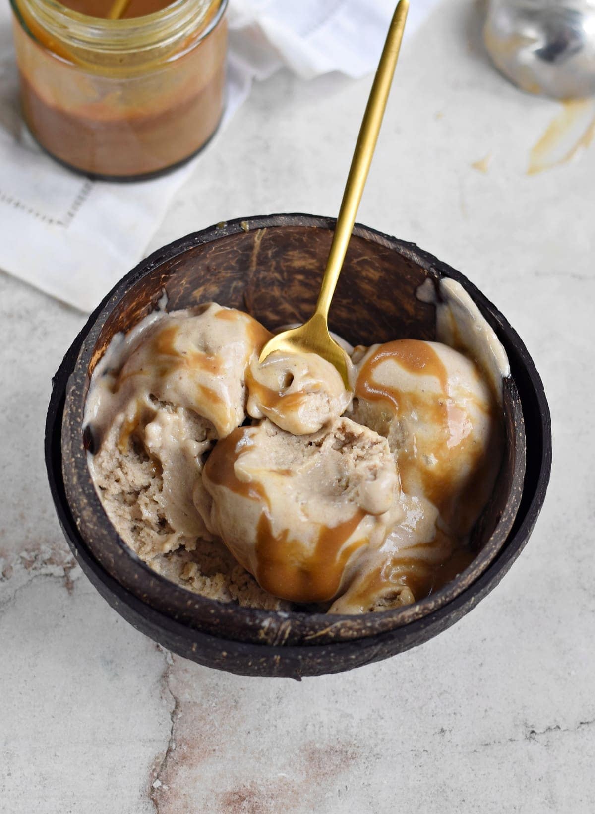 creamy vegan soft serve with caramel sauce in bowl with spoon