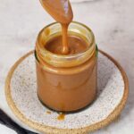 drizzling vegan caramel sauce in jar with spoon