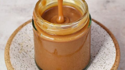 drizzling vegan caramel sauce in jar with spoon